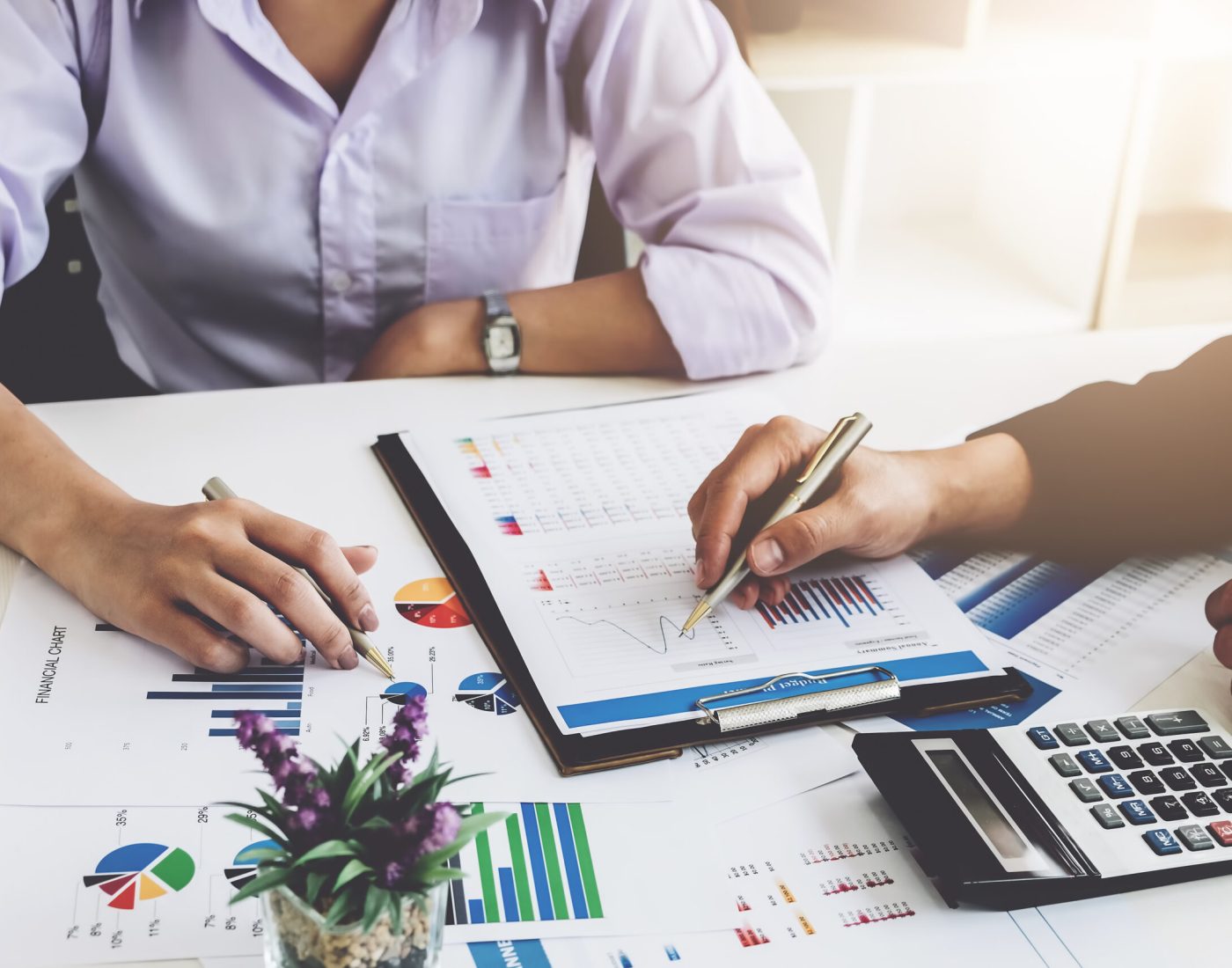 Business financial concept. busines sman and partner pointing graph paper are meeting to plan sales to meet targets set in next year.